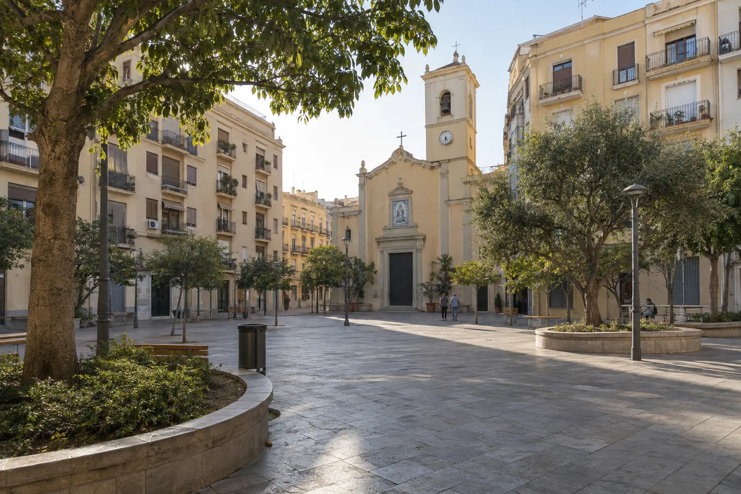 Plaza peatonal con iglesia de campanario y edificios residenciales de inspiración valenciana